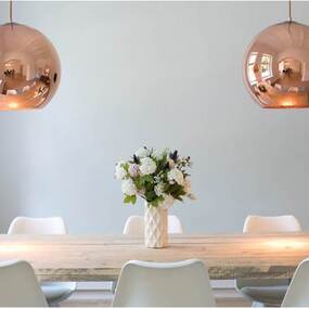 Moderner Essbereich mit Holztisch, weißen Stühlen, Blumenstrauß und Kupferlampen.